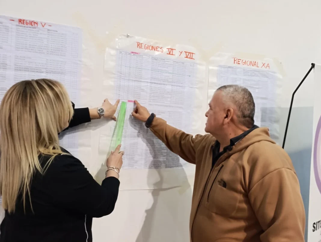Dos personas consultan planillas de cargos colocadas en una pared durante los concursos de primaria en Chaco.