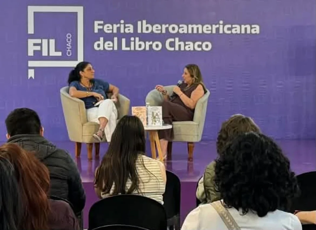 Dos mujeres conversan en el escenario de la Feria del Libro, frente al público.