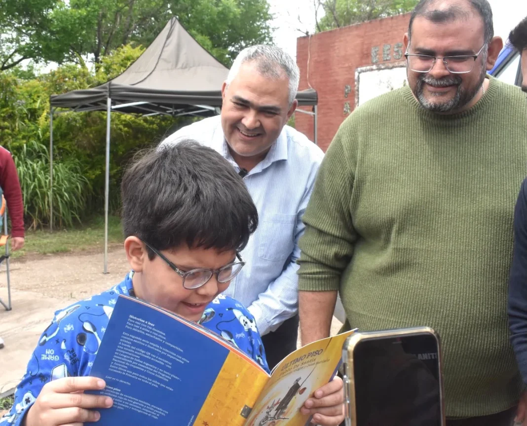 Un niño con anteojos lee un libro junto a integrantes del operativo Ver para ser Libres